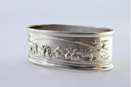 Argola de guardanapo em prata em forma oval com coelhos revelados.